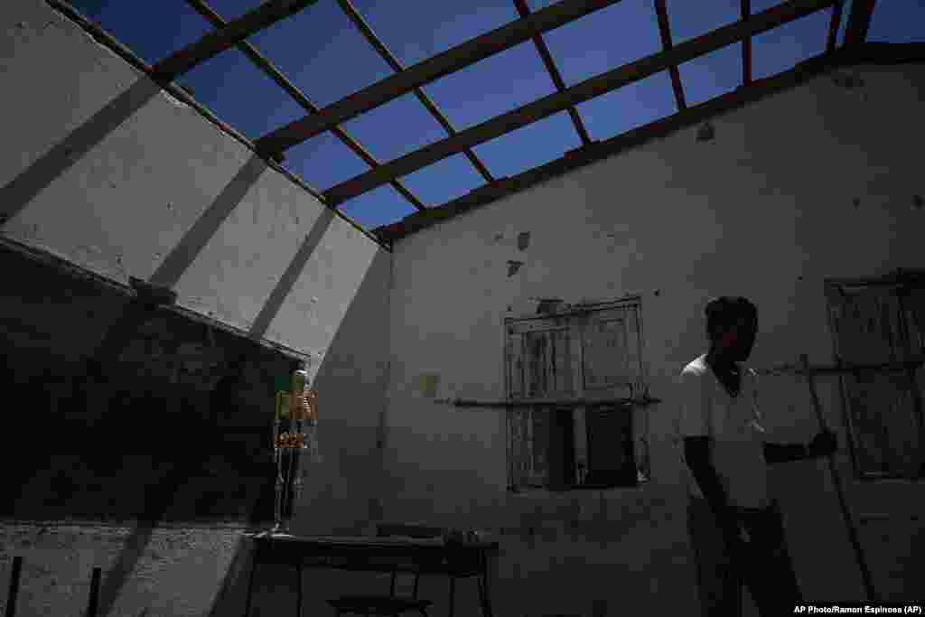 Un voluntario limpia un aula sin techo en una escuela gravemente dañada por el huracán Ian en La Coloma.