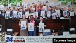 Legisladores en el Congreso de Colombia portan carteles con los rostros de los presos políticos de la región de Latinoamérica. En el medio en primera fila, una ficha de Loreto Hernández, preso del 11J.