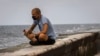 Un hombre echa una rosa al mar en el Malecón de La Habana en medio de la pandemia de coronavirus. (AP/Ramon Espinosa)