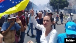 La opositora María Corina Machado sostiene una bandera venezolana al revés en protesta contra el gobierno de Maduro.