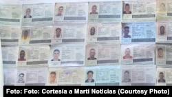 Imágenes de pasaportes cubanos reclutados por Rusia en una pancarta que llevaron activistas que se manifestaron en Washington contra la guerra een Ucrania