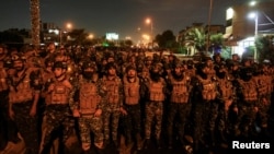 Fuerzas de seguridad iraquíes observan a partidarios de grupos armados chiítas iraquíes durante una protesta contra Estados Unidos cerca de la embajada de EEUU y otras misiones en Bagdad, Irak, el 18 de octubre de 2023. REUTERS/Ahmed Saad