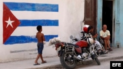Un niño pasa junto a una pintura de la bandera cubana en una pared, en La Habana. (Archivo)