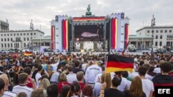 Simpatizantes de la selección nacional alemana de fútbol siguen por televisión la salida de los jugadores de Brasil en la llamada "Milla del aficionado" en la Puerta de Brandeburgo en Berlín (Alemania).