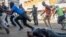 Un hombre cae al suelo tras ser disparado en la espalda por las fuerzas de seguridad durante una protesta organizada por simpatizantes del Movimiento por el Cambio Democrático (MDC) contra el conteo de votos tras las elecciones del país, en Harare, Zimbabue, el 1 de agosto de 2018. 