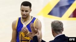 El baloncestista Stephen Curry (i) recibe instrucciones del director técnico Steve Kerr (d).