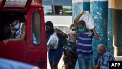 Cubanos cargan sus compras. YAMIL LAGE / AFP